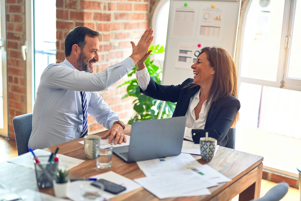 Man and woman celebrating with a high-five in front of a laptop, boosting seo for ramsgate business